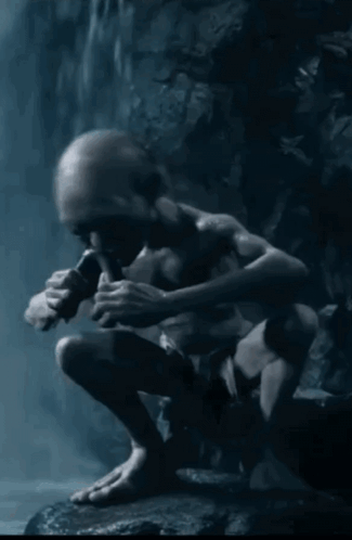 A Gollum Sitting On A Rock Playing A Flute In The Dark GIF