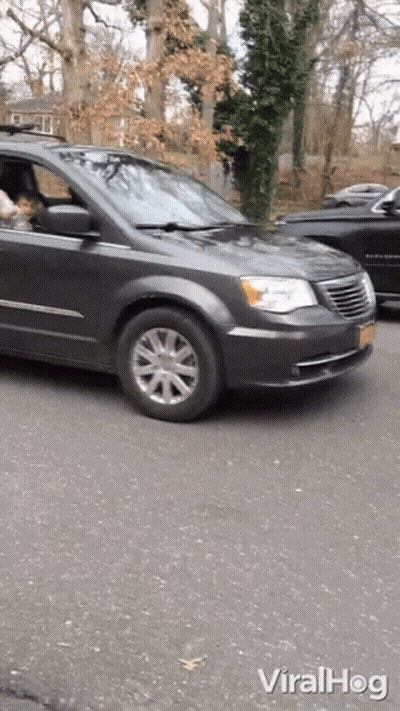 A Gray Chrysler Minivan Is Driving Down The Street GIF