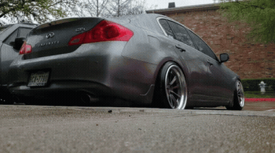 A Gray Infiniti Is Parked On The Side Of A Road GIF