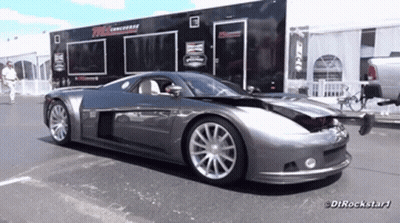 A Gray Sports Car Is Parked In Front Of A Trailer That Says Dtrockstar1 On It GIF