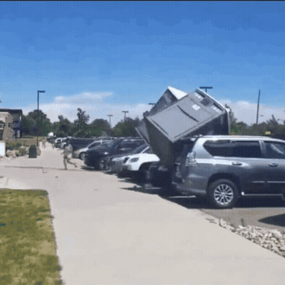A Gray Suv Is Parked In A Parking Lot With A Fridge In The Back GIF