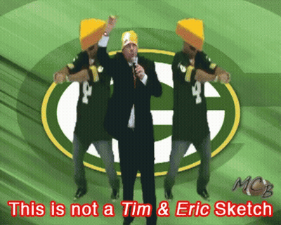 A Green Bay Packers Logo Is Behind A Man In A Suit GIF