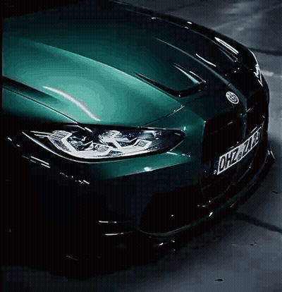 A Green Bmw M3 Is Driving Down A Parking Garage . GIF
