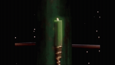 A Green Candle In A Gold Candle Holder Is Glowing In The Dark GIF