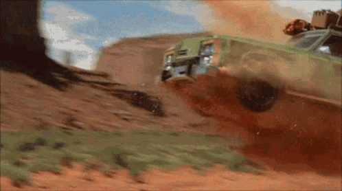 A Green Car Is Driving Down A Dirt Road And Crashing Into A Tree . GIF