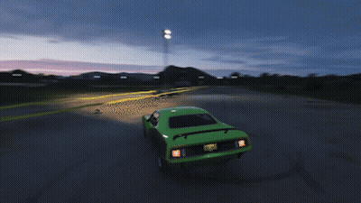A Green Car Is Driving Down A Road With A Sunset In The Background GIF