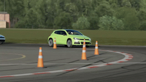 A Green Car Is Driving On A Race Track Next To A Traffic Cone GIF