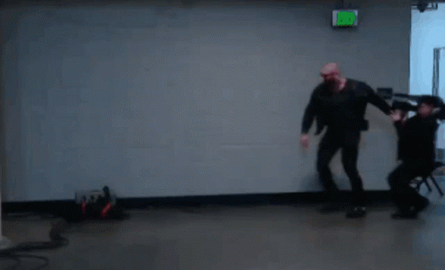 A Green Exit Sign Hangs Above A Man And Woman Dancing GIF