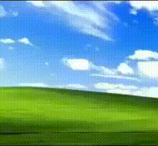 A Green Field With A Blue Sky And Clouds Behind It GIF