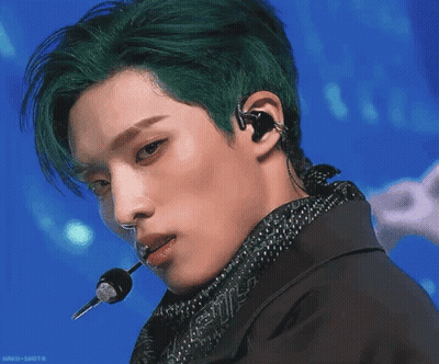A Green Fish Is Swimming In The Water With A Person In The Background GIF