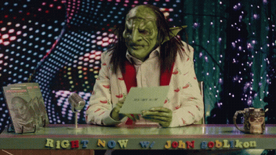 A Green Goblin Is Sitting At A Desk With The Words Right Now W/ John Goblikon GIF