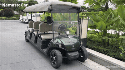 A Green Golf Cart Is Parked On A Sidewalk With The Words Namaste Car Written On The Bottom GIF