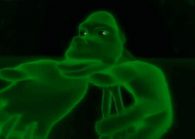 A Green Gorilla With Glowing Eyes Is Holding A Microphone In The Dark . GIF