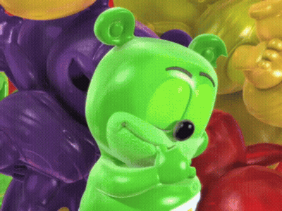 A Green Gummy Bear Standing In Front Of A Pile Of Gummy Bears GIF