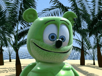 A Green Gummy Bear With Blue Eyes Is Standing On A Beach GIF