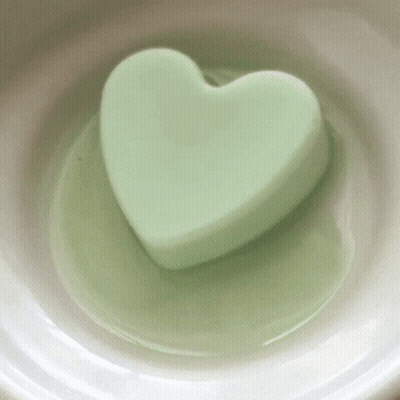 A Green Heart Shaped Soap Is In A White Bowl GIF