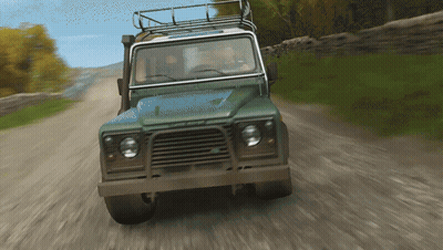 A Green Land Rover Is Driving Down A Dirt Road With Trees In The Background GIF