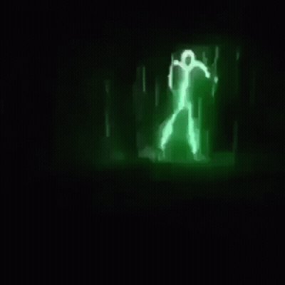 A Green Light Is Shining In The Dark And Looks Like A Person Walking . GIF