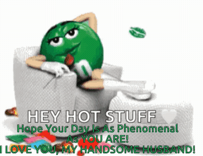 A Green M & M Sitting In A Chair With A Rose In His Mouth GIF