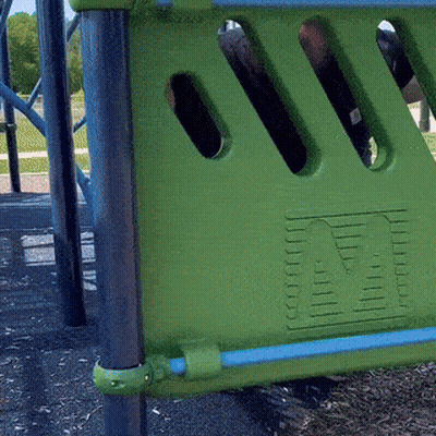 a green playground with a blue railing and a green fence with the letter m on it