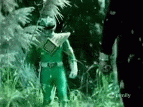 A Green Power Ranger Is Standing In The Grass Next To A Man . GIF