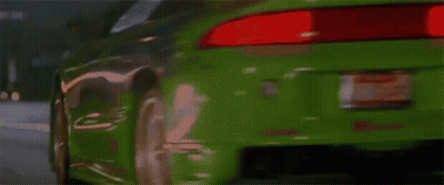 A Green Sports Car Is Driving Down A Street And Has The Word Turbo On The Hood GIF