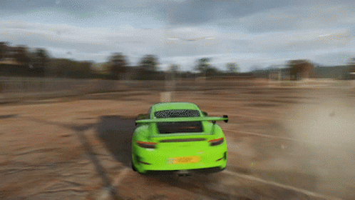 A Green Sports Car Is Driving On A Dirt Road . GIF
