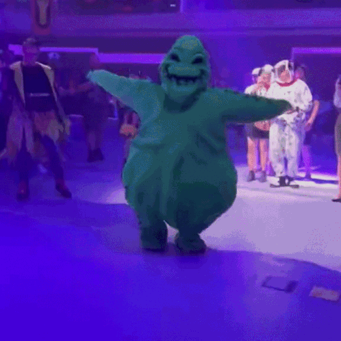 Green Stuffed Animal Dancing On Stage GIF
