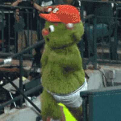 A Green Stuffed Animal Wearing A Red Hat And Diapers GIF