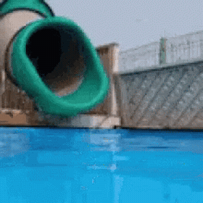 A Green Tube Is Going Down A Water Slide Into A Pool GIF