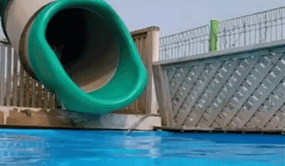 A Green Water Slide Is Going Down A Pool GIF