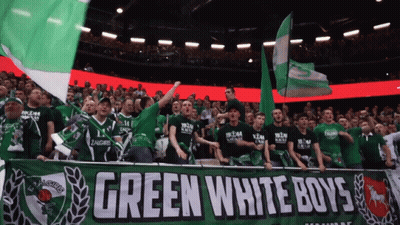 A Green White Boys Banner Is Displayed In A Crowd GIF