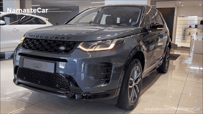 A Grey Land Rover Discovery Is Shown In A Showroom GIF