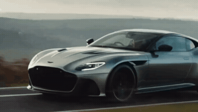 A Grey Sports Car Is Driving Down A Road GIF