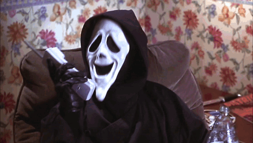 A Grim Reaper Talking On A Cell Phone In Front Of A Floral Wall GIF