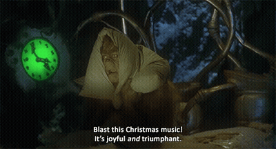 A Grinch Says Blast This Christmas Music It 'S Joyful And Triumphant In Front Of A Clock GIF