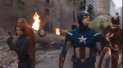 A Group Of Avengers Including Captain America And Black Widow Are Walking Through A Destroyed City GIF