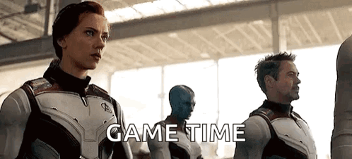 A Group Of Avengers Standing Next To Each Other In A Room With The Words `` Game Time '' Written On The Bottom . GIF