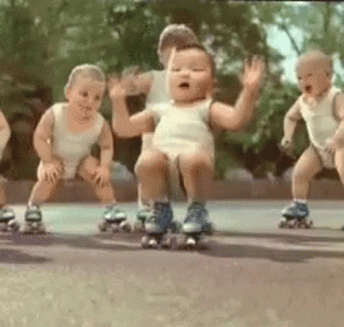 A Group Of Babies Wearing Roller Skates Are Dancing Together . GIF
