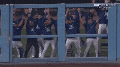 A Group Of Baseball Players Are Behind A Fence With Fox World Series Written Above Them GIF