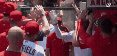 A Group Of Baseball Players Are Giving Each Other A High Five While Standing In A Dugout . GIF