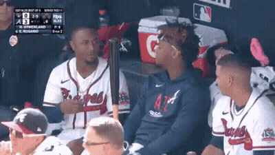 A Group Of Baseball Players Are Sitting In A Dugout With A Bat . GIF