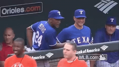 A Group Of Baseball Players Are Sitting In The Dugout With A Bank Of America Banner In The Background GIF