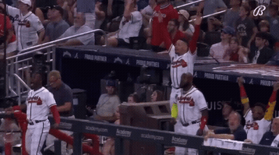 A Group Of Baseball Players Are Standing In A Dugout With A Banner That Says Proud Partner GIF