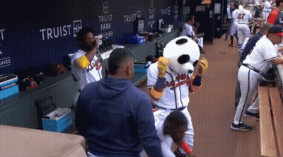 A Group Of Baseball Players Are Standing In A Dugout With A Panda Mascot GIF