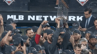 A Group Of Baseball Players Holding A Trophy In Front Of A Mlb Network Banner GIF