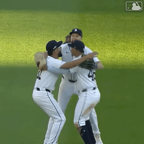 A Group Of Baseball Players Hugging Each Other On The Field GIF