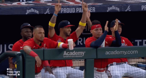 A Group Of Baseball Players Sitting In A Dugout With Academy Sports Outdoors Written On The Wall Behind Them GIF
