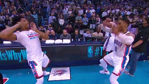 A Group Of Basketball Players Are Dancing On A Court In Front Of A Crowd GIF