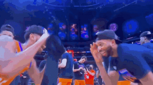 A Group Of Basketball Players Are Huddled Together In A Stadium . GIF